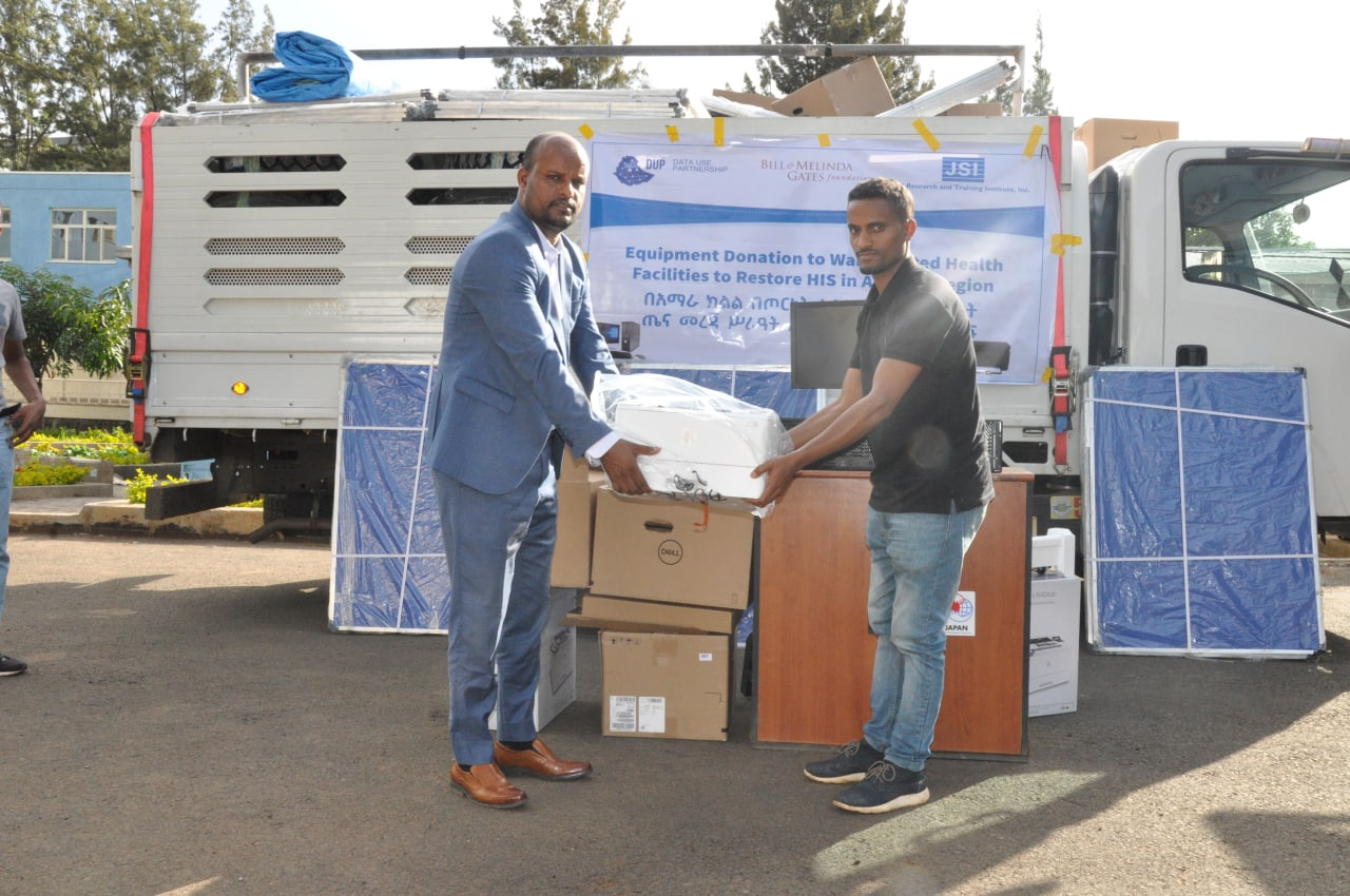 Abdelkarim Mengistu, left, receives equipment from Birhanu Taye, DUP regional staff member