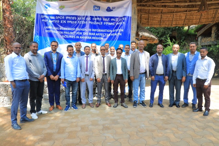 Launch ceremony participants stand before a banner for Launching Workshop on Health Information System Restoration Project for the War Affected Health Facilities in Amhara Region