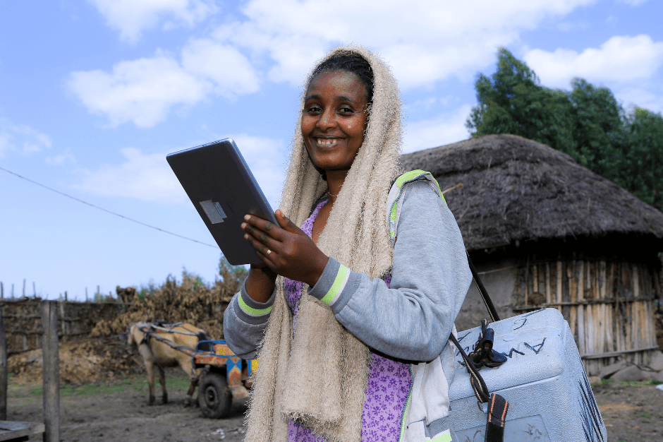 Team member standing outdoors smiling as she holds her data collection tablet.